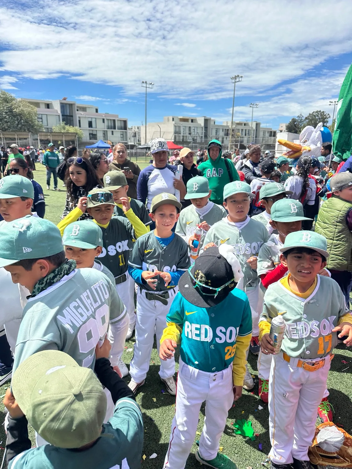 Un grupo de jugadores y familiares en el campo de béisbol.